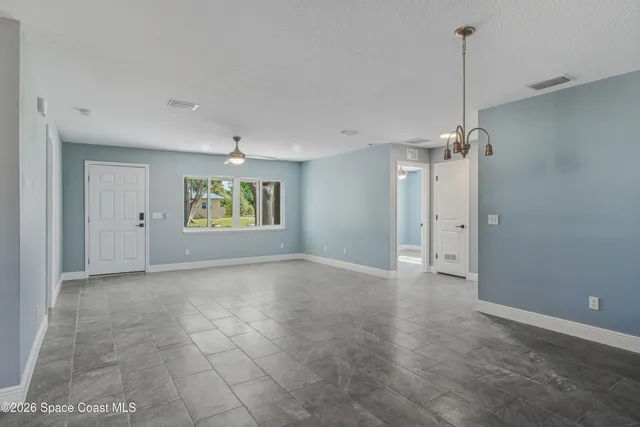 a view of an empty room and window chandelier fan