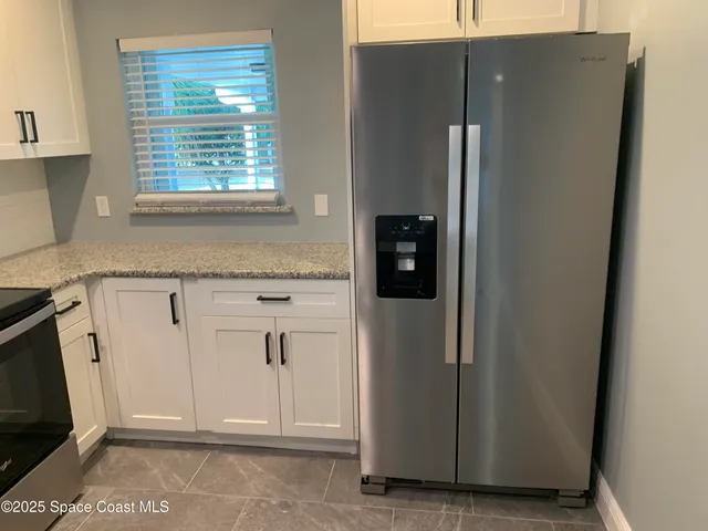 a view of a kitchen with white cabinets and refrigerator