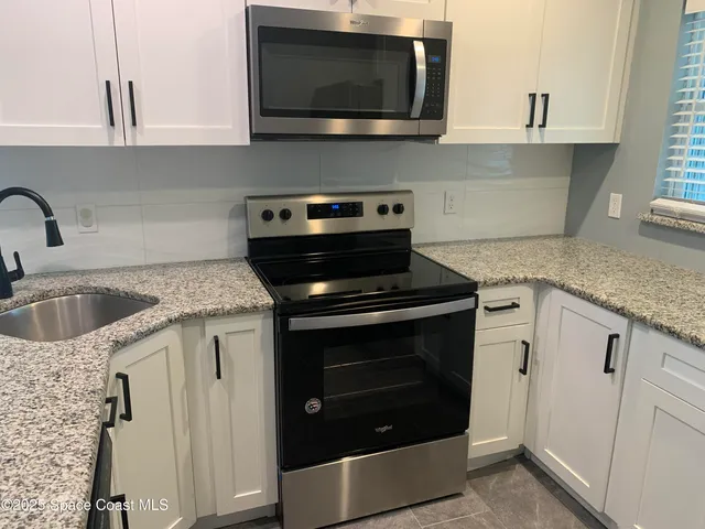 a kitchen with stainless steel appliances granite countertop a sink stove a microwave and view