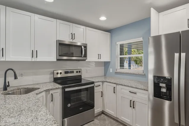 a kitchen with refrigerator a stove a sink and cabinets