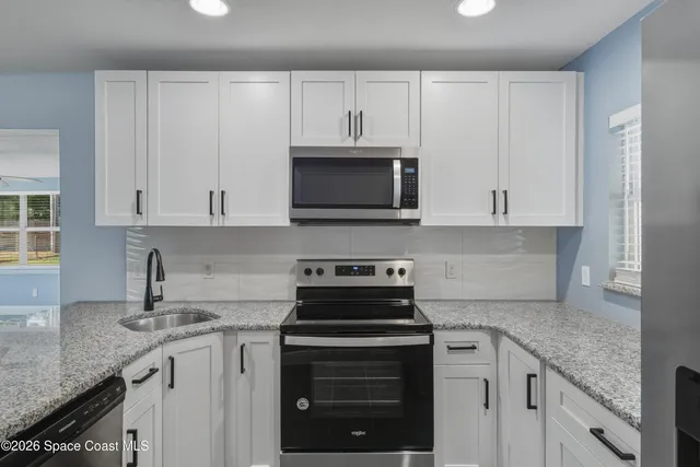 a kitchen with granite countertop white cabinets and a stove a oven with white countertops