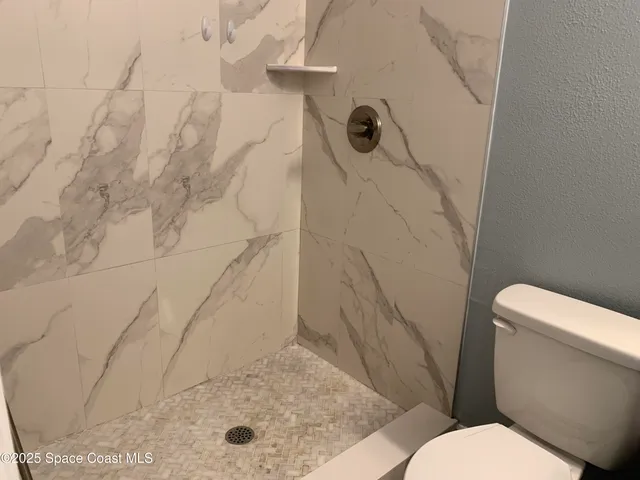a white toilet sitting next to a shower