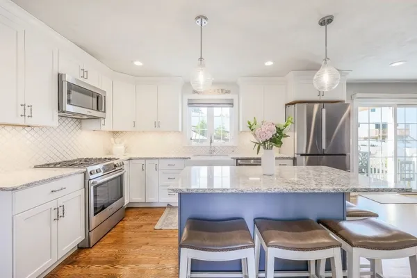 a kitchen with stainless steel appliances granite countertop a kitchen island hardwood floor sink stove and microwave