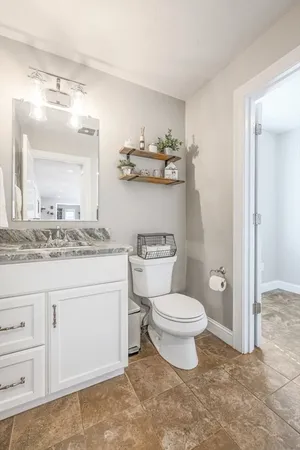 a bathroom with a granite countertop toilet a sink and a mirror