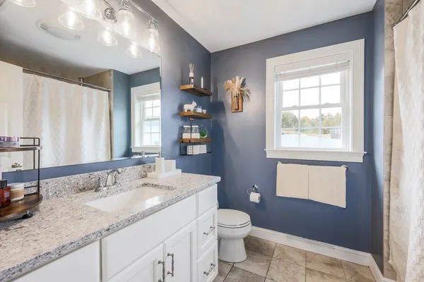 a bathroom with a granite countertop sink a mirror and a toilet