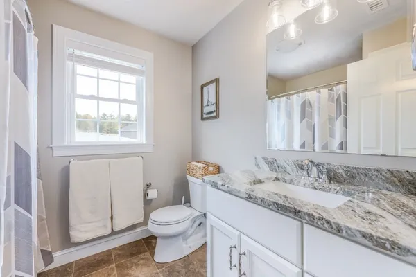 a bathroom with a granite countertop sink a toilet and a window