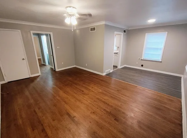 a view of an empty room with wooden floor and a window