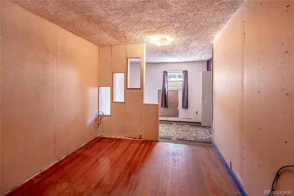a view of an empty room with wooden floor and closet