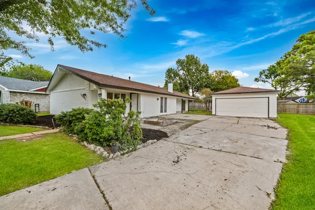 a view of a house with a yard and a large tree