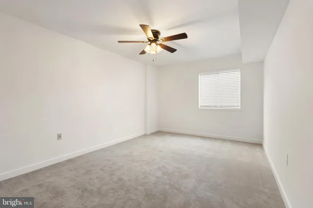 an empty room with a window and a fan