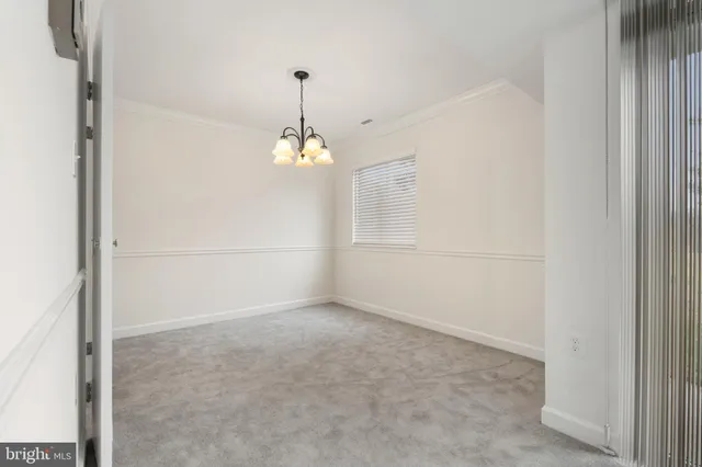 an empty room with chandelier fan and windows