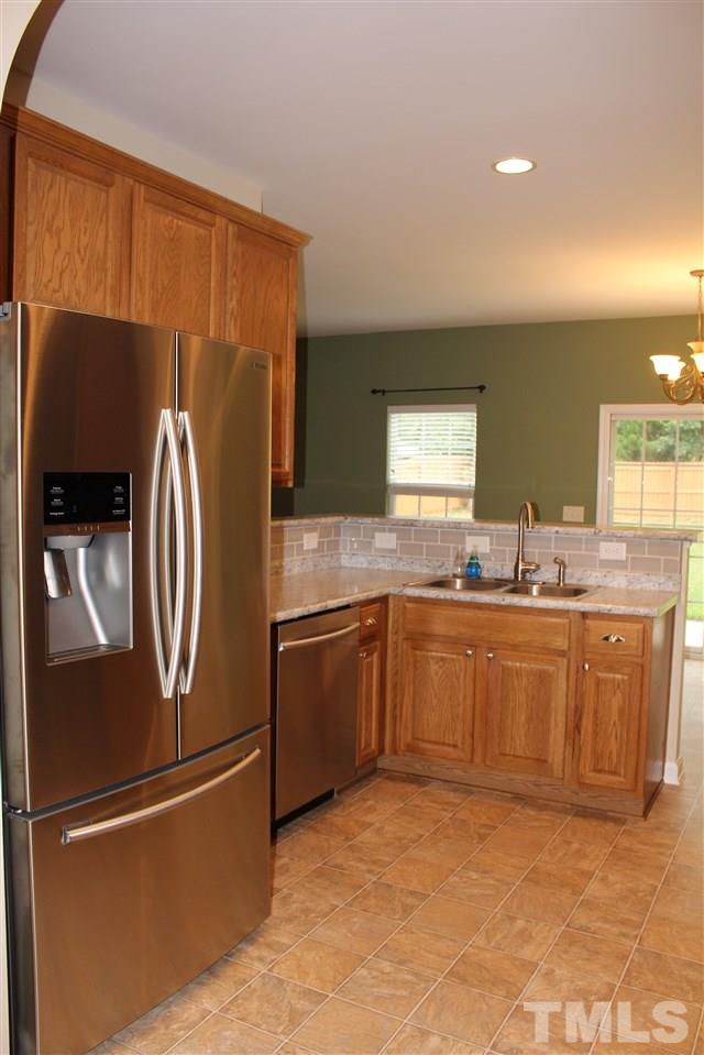 5321 Neuse Forest Road Raleigh, NC 27616 - Photo 9 of 25 a kitchen with stainless steel appliances granite countertop a refrigerator a sink a stove with wooden cabinets