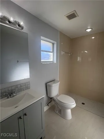 a bathroom with a sink a toilet a mirror and shower