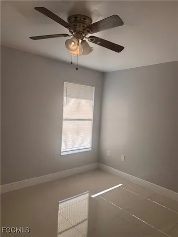 an empty room with a chandelier fan and windows