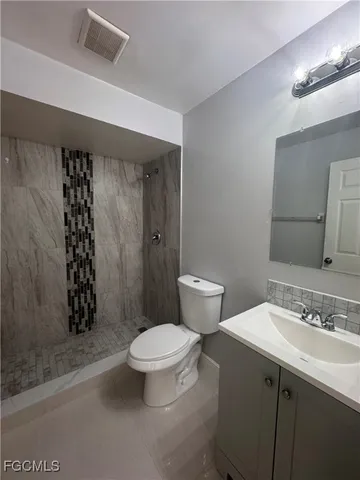 a bathroom with a sink a toilet a mirror and shower