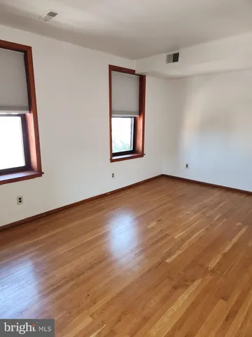 a view of an empty room with wooden floor and closet