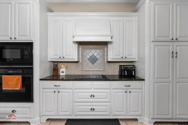 a kitchen with granite countertop white cabinets and stainless steel appliances