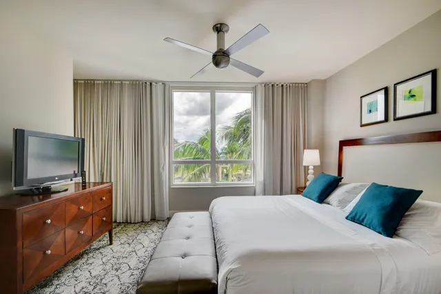 a bedroom with a large bed and a flat tv screen on dresser
