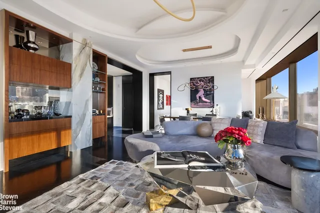 a living room with couches a coffee table and chandelier