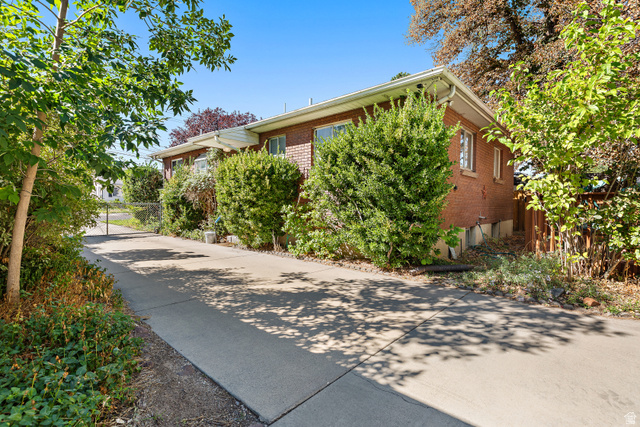 664 Wasatch Street Midvale, UT 84047 - Photo 18 of 33 Brick exterior with white soffits and fascia, mature landscaping, and an extended concrete driveway