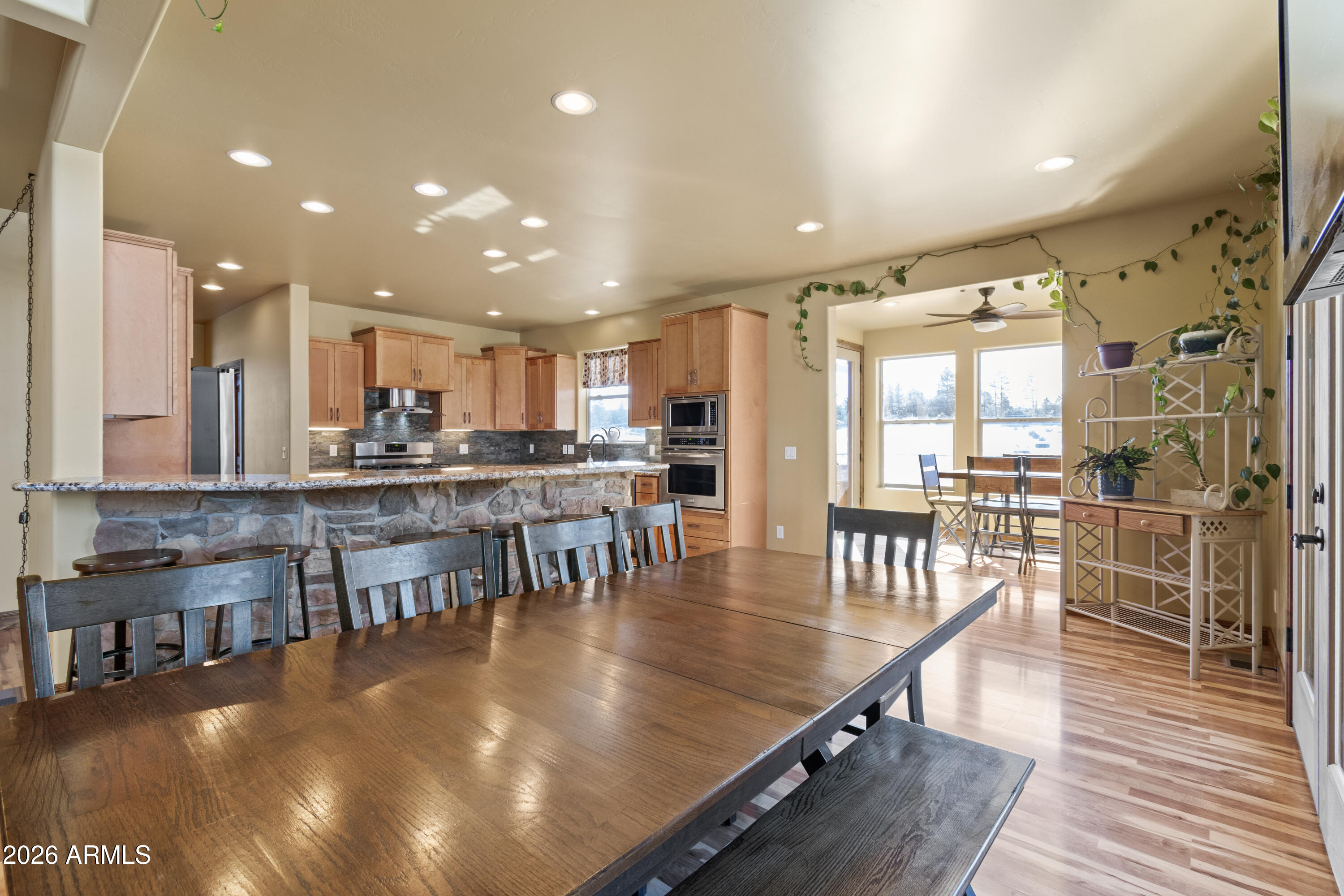 816 Fern Way Show Low, AZ 85901 - Photo 19 of 88 a dining room with stainless steel appliances a dining table chairs and couches with wooden floor
