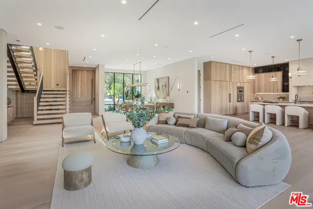 a living room with furniture kitchen view and a large window
