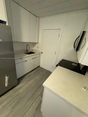 a kitchen with a sink a stove and white cabinets