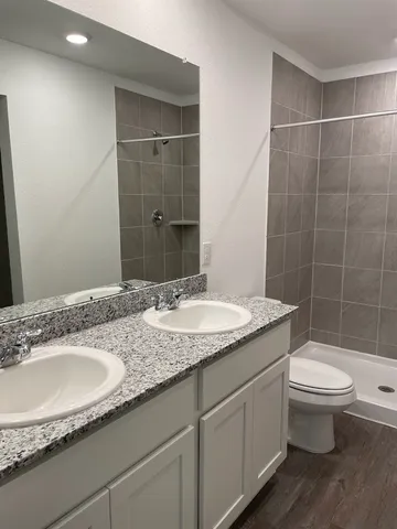 a bathroom with a granite countertop sink a toilet a mirror and shower