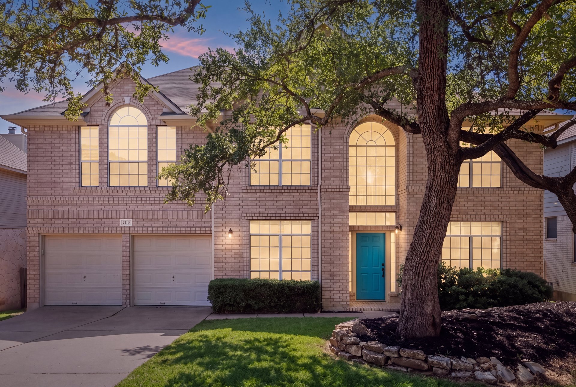 7113 Bending Oak Road Austin, TX 78749 - Photo 1 of 39 Mature trees frame a classic brick exterior featuring towering arched windows and a double garage.