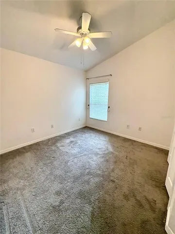 an empty room with a chandelier fan and windows