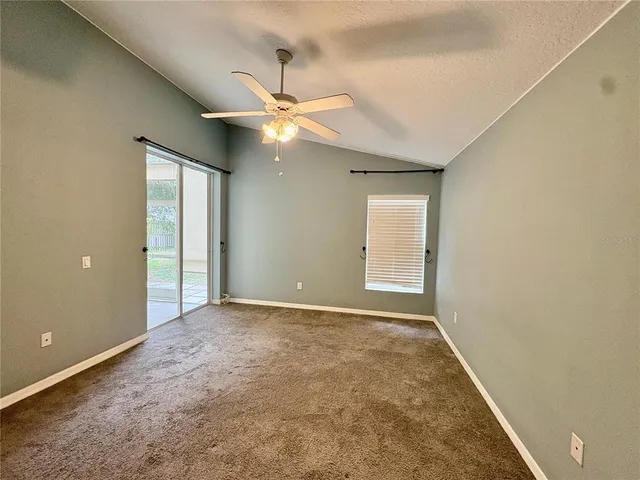 an empty room with chandelier fan and windows