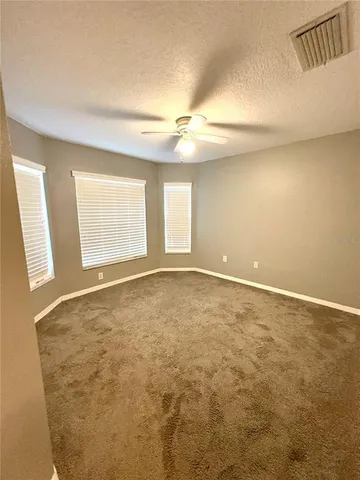 an empty room with windows and fan