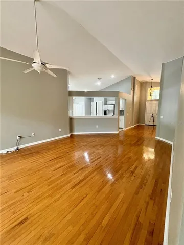 a view of empty room with wooden floor and fan
