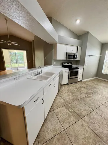 a large white kitchen with a sink and dishwasher a stove top oven with wooden floor