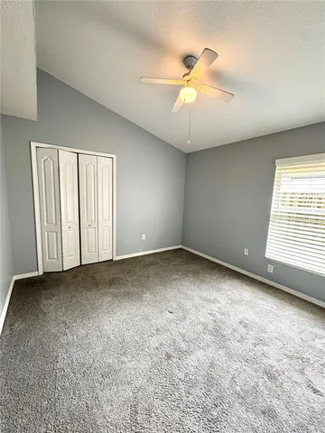 an empty room with windows and fan