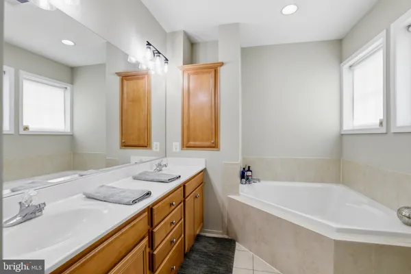 a bathroom with a granite countertop tub sink and mirror