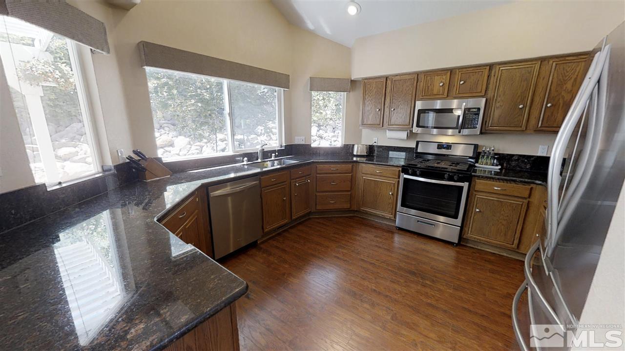 1970 Honey Ridge Drive Reno, NV 89511 - Photo 4 of 25 a kitchen with stainless steel appliances granite countertop wooden floors a stove a microwave a sink and dishwasher with wooden floor