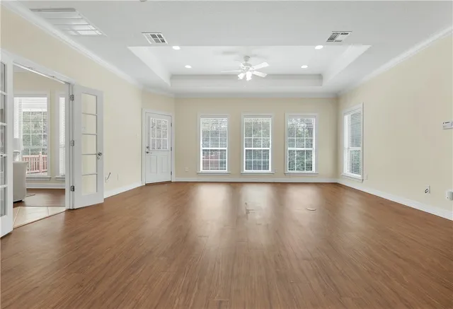 a view of an empty room with wooden floor and a window