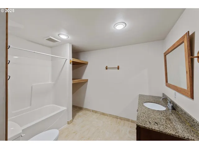 a bathroom with a granite countertop sink mirror vanity and bathtub