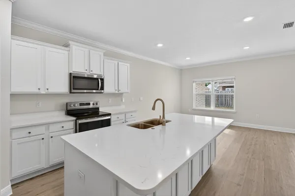 a kitchen with stainless steel appliances a microwave a stove a sink dishwasher a refrigerator and white cabinets with wooden floor