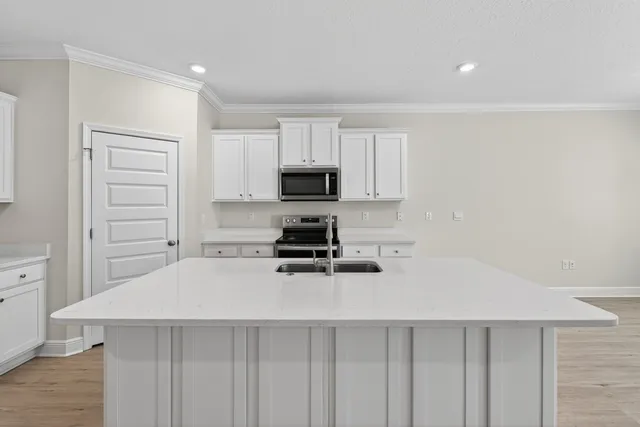 a kitchen with granite countertop a stove top oven a sink a counter space and cabinets