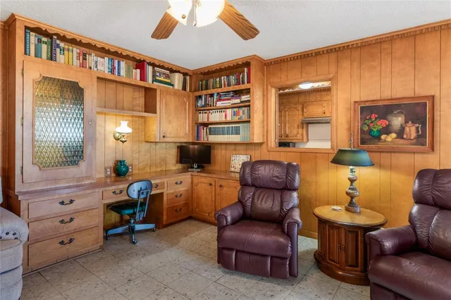 a living room with furniture a desk and chair with a bookshelf