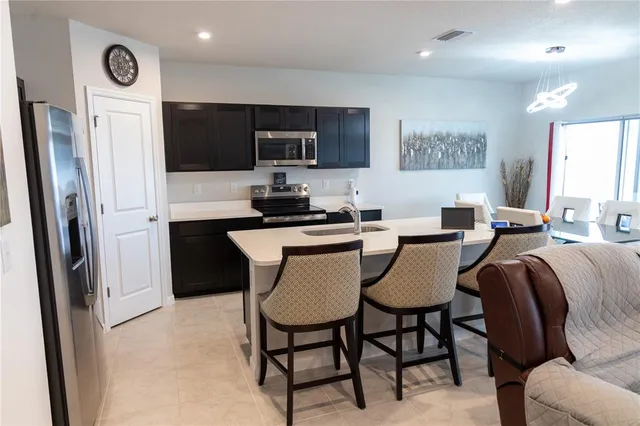 a dining room with stainless steel appliances a table chairs and a refrigerator