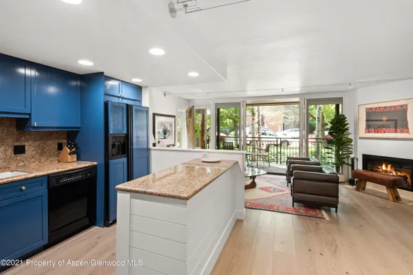 a living room with stainless steel appliances granite countertop furniture a refrigerator a couch and a kitchen view