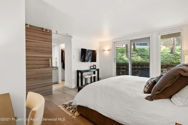 a spacious bedroom with a bed and glass window