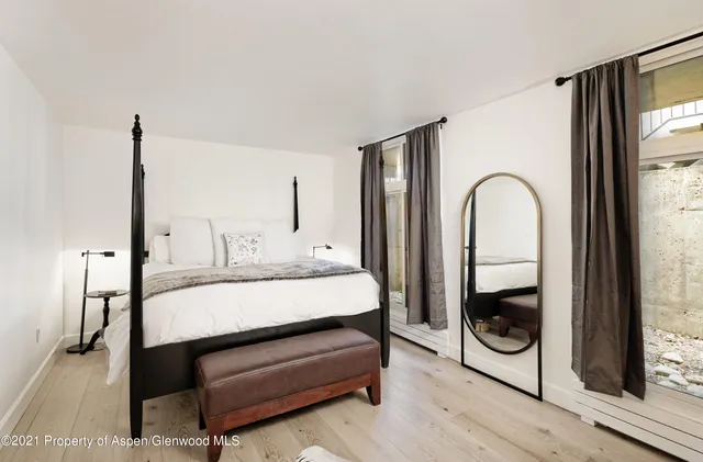 a bedroom with a bed a mirror and glass door