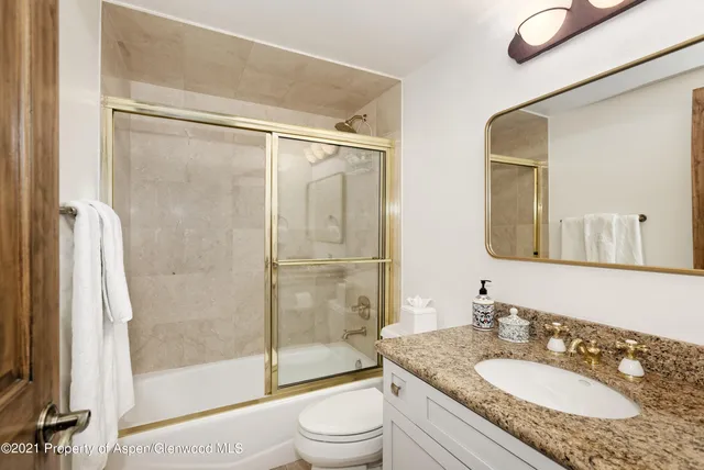 a bathroom with a granite countertop sink toilet mirror and shower