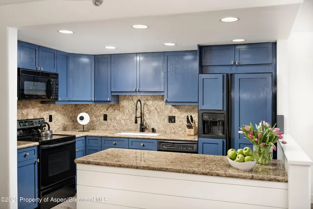 a kitchen with granite countertop stainless steel appliances stove microwave refrigerator and cabinets