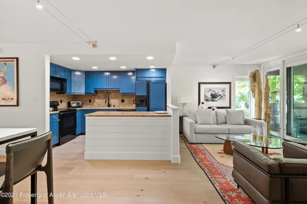 a view of kitchen with kitchen island a living room a refrigerator cabinets and living room view