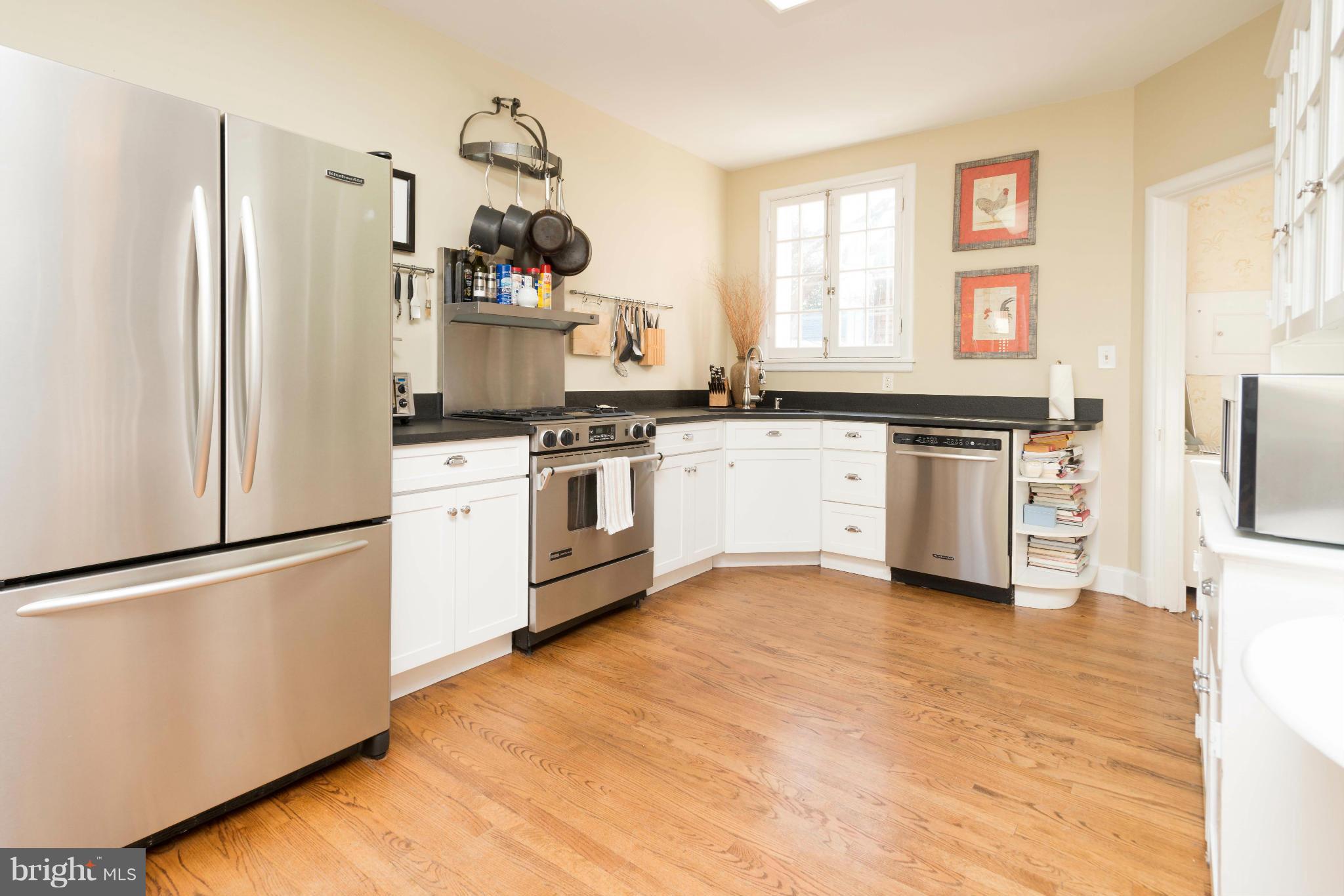 207 Witherspoon Road Baltimore, MD 21212 - Photo 8 of 28 a kitchen with stainless steel appliances granite countertop a stove top oven a sink a refrigerator and white cabinets with wooden floor